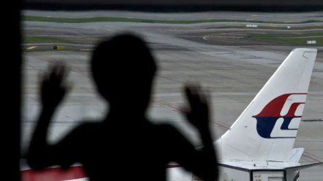 Niño observa una aeronave de la flota Malaysia Airlines antes de su despegue.