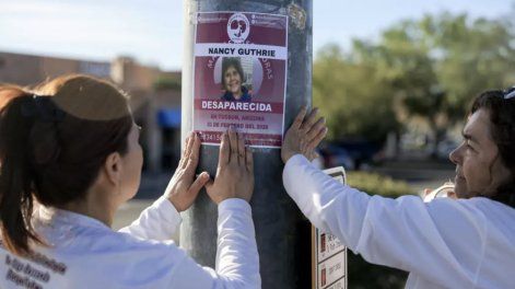Rachel Navarro (izq.) y Lidia Hernández, de las Madres Buscadoras de Sonora, colocan un cartel con una fotografía de la desaparecida Nancy Guthrie cerca de su casa en Tucson (Arizona) el 24 de febrero de 2026.