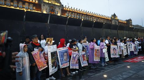 Personas sostienen carteles en una protesta por el aniversario de la desaparición de 43 estudiantes de Ayotzinapa, este viernes en Ciudad de México (México). 