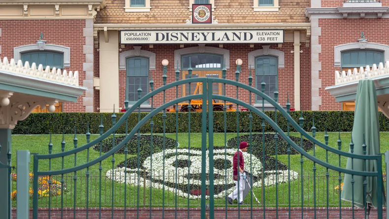 Un empleado limpia los terrenos detrás de las puertas cerradas del Parque Disneyland