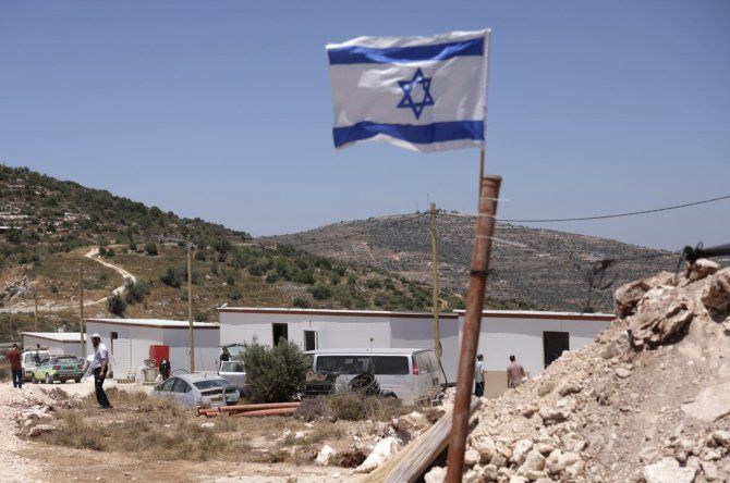 Una bandera nacional israelí ondea cerca de estructuras prefabricadas, cerca del asentamiento de Maale Levona en la Cisjordania ocupada.