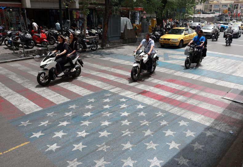 Conductores iraníes pasan por encima de una pintura que representa las banderas de Estados Unidos e Israel en una calle de Teherán, Irán, el 4 de mayo de 2026.
