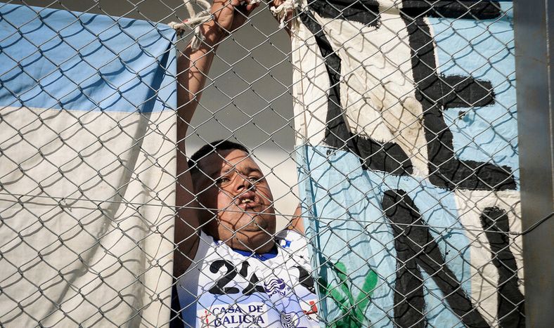 Hincha cuelga una bandera en una tribuna durante un partido fútbol. Foto: Javier Calvelo / adhocFOTOS