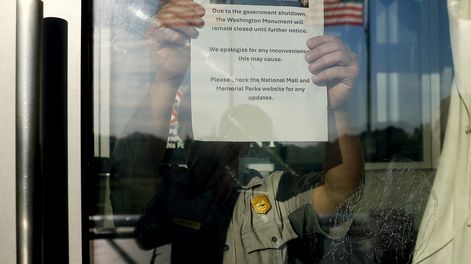 Un funcionario coloca un cartel en el que se comunica el cierre de la atención al público durante el shutdown.