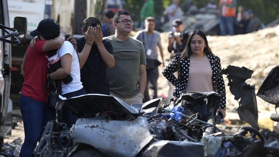 Familiares de las víctimas del atentado ocurrido en la Vía Panamericana lloran este domingo frente a los escombros de los vehículos destruidos, en Cajibío (Colombia).