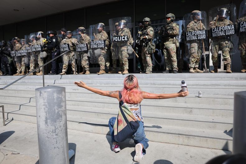 Una manifestante se arrodilla frente a miembros de la Guardia Nacional de California frente al edificio federal Edward R. Roybal en Los Ángeles, California (Estados Unidos).