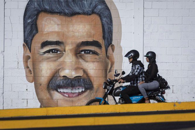 Personas pasan frente a una pared con un dibujo alusivo al presidente de Venezuela, Nicolás Maduro, este martes en Caracas (Venezuela).