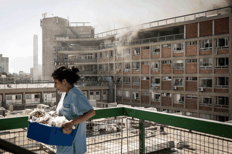 Una enfermera transporta suministros médicos frente a un edificio con columnas de humo en el Hospital Soroka tras un ataque con misiles iraníes en Beersheba, al sur de Israel, el 19 de junio de 2025