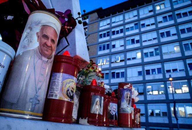 Una vela con la imagen del papa Francisco, al pie de la estatua de San Juan Pablo II en las afueras del Hospital Universitario Gemelli donde se encuentra hospitalizado.
