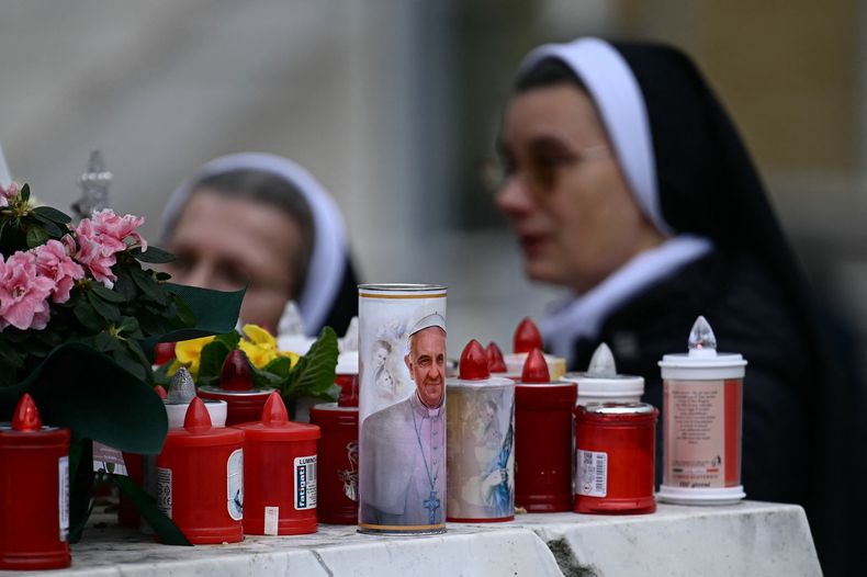 Una vela con el retrato del papa Francisco se coloca a los pies de una estatua de Juan Pablo II en el exterior del hospital Gemelli, donde el papa Francisco está internado en Roma, el 20 de febrero de 2025