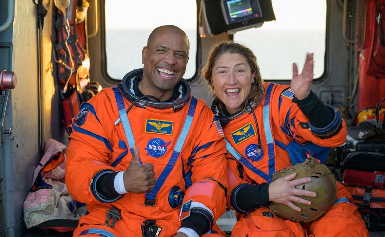El piloto de la misión Artemis II, el astronauta Victor Glover (i), y la especialista de misión, la astronauta Christina Koch (d), saludando desde un helicóptero MH-60 Seahawk de la Armada estadounidense tras salir de la nave espacial Orion este viernes, en el océano Pacífico, frente a la costa de California (Estados Unidos).
