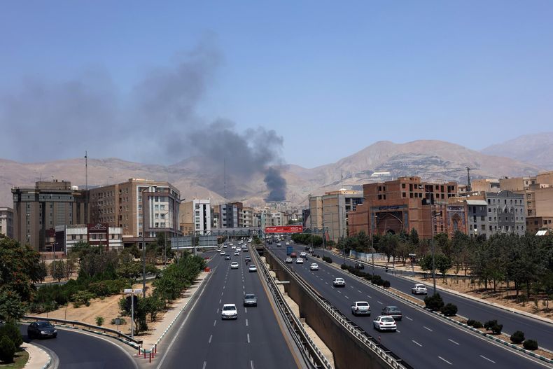 Vehículos circulan por una autopista mientras se eleva humo al fondo desde una refinería de petróleo, al noroeste de Teherán, Irán, el 16 de junio de 2025