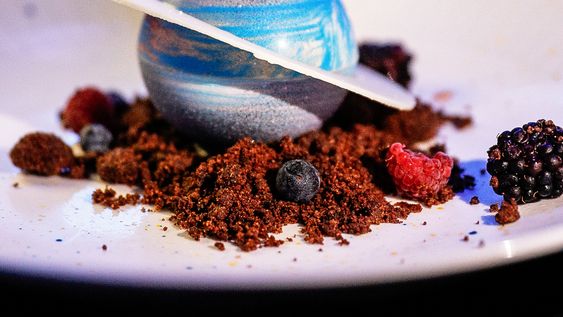 Saturno, mousse de yogur y lima con núcleo&nbsp;de frutos rojos sobre nebulosa de cacao.