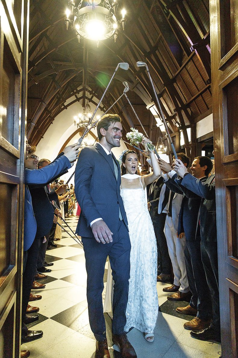 Martín Payovich y Valentina Soldo saliendo de la iglesia, debajo del puente de palos de golf que fue una sorpresa para el novio