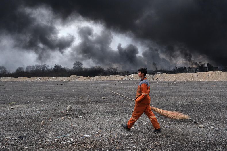 Un barrendero camina por delante del Depósito de Petróleo del Noroeste de Teherán que fue atacado por Israel.