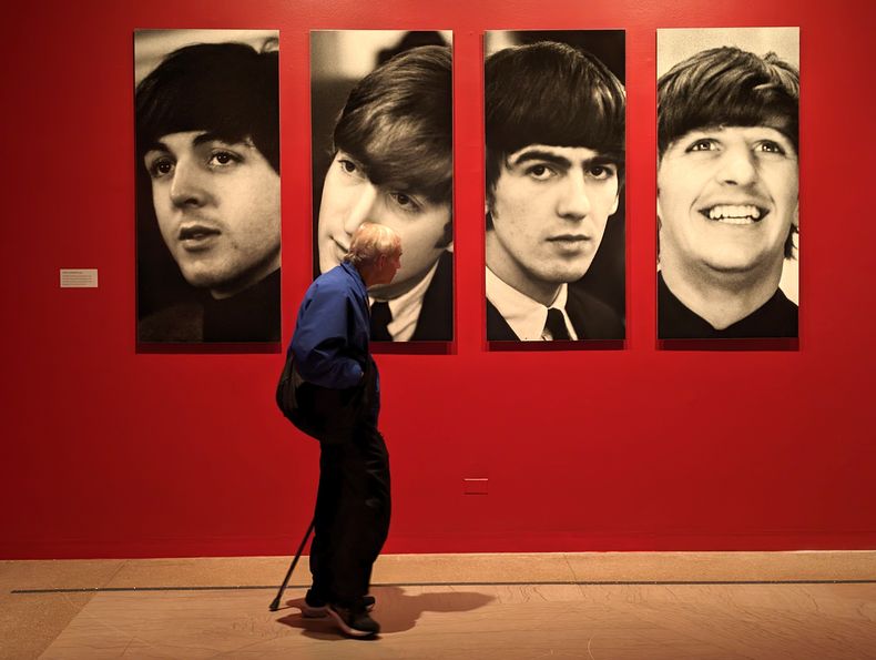 Una persona camina frente a retratos de los integrantes de la banda británica The Beatles durante la exposición “Ojos de la tormenta“, en el Museo de Brooklyn, en Nueva York, en 2024.