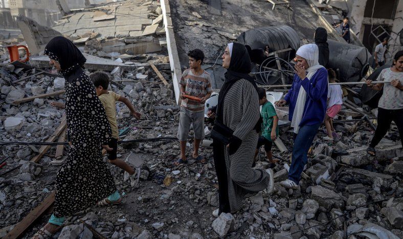 Personas, caminando sobre escombros, abandonan la zona tras el ataque israelí en la calle Omar al-Mukhtar de la ciudad de Gaza, el 3 de octubre de 2025.