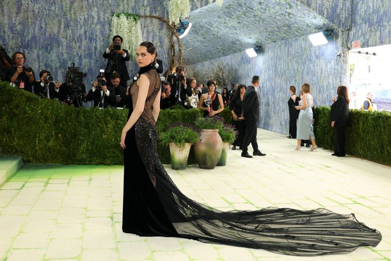 Cara Delevigne pisó la alfombra roja con un esbelto vestido negro de cuello halter de Ralph Lauren, con mangas de tul negro y una larga cola estilo pavo real. 