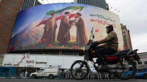 La gente pasa frente a un enorme cartel publicitario que muestra a los difuntos líderes supremos iraníes, el ayatolá Ruhollah Jomeini, el ayatolá Ali Jamenei , y al nuevo líder supremo iraní, el ayatolá Mojtaba Jamenei (d), en la Plaza Valiasr de Teherán, Irán, este martes.&nbsp;