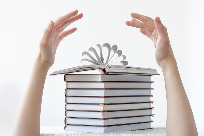 una-pila-de-libros-encima-de-un-libro-abierto-y-dos-manos-sobre-los-libros-el-concepto-de-aprendizaje-escuela-lectura-literatura