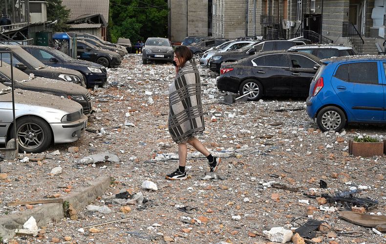 Residente camina entre autos dañados al salir de un edificio parcialmente destruido después de ataques con drones en Kiev. Foto: Oleksandr Popenko, PIJL