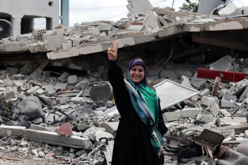 Una mujer que ha regresado a su pueblo hace el signo de la victoria junto a un edificio destruido tras los ataques israelíes en la aldea de Maaroub, en el sur del Líbano, el 15 de junio de 2026, después del anuncio de un marco preliminar mediado por Estados Unidos e Irán para poner fin a las hostilidades militares regionales y levantar el bloqueo naval del estrecho de Ormuz.