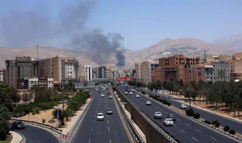 Vehículos circulan por una autopista mientras se eleva humo al fondo desde una refinería de petróleo, al noroeste de Teherán, Irán, el 16 de junio de 2025