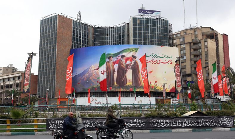 La gente pasa frente a una enorme valla publicitaria que muestra a los difuntos líderes supremos iraníes, el ayatolá Ruhollah Jomeini (izq.), el ayatolá Alí Jamenei (centro), y el nuevo líder supremo iraní, el ayatolá Mojtaba Jamenei (der.), en la plaza Valiasr de Teherán.