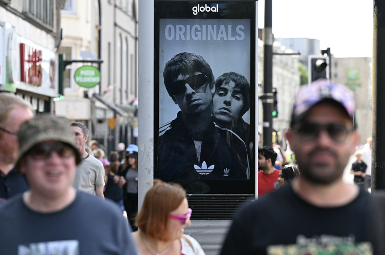 Un anuncio de la banda de rock británica Oasis se ve en el centro de Cardiff el 4 de julio de 2025, antes del concierto inaugural de su esperadísima gira de reunión, casi 16 años después de su última actuación juntos