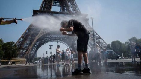 Un empleado municipal rocía agua para refrescar a los turistas frente a la Torre Eiffel en París, el 2 de julio de 2025, mientras una ola de calor azota Francia