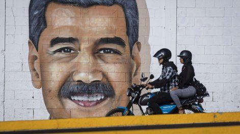 Personas pasan frente a una pared con un dibujo alusivo al presidente de Venezuela, Nicolás Maduro, este martes en Caracas (Venezuela).