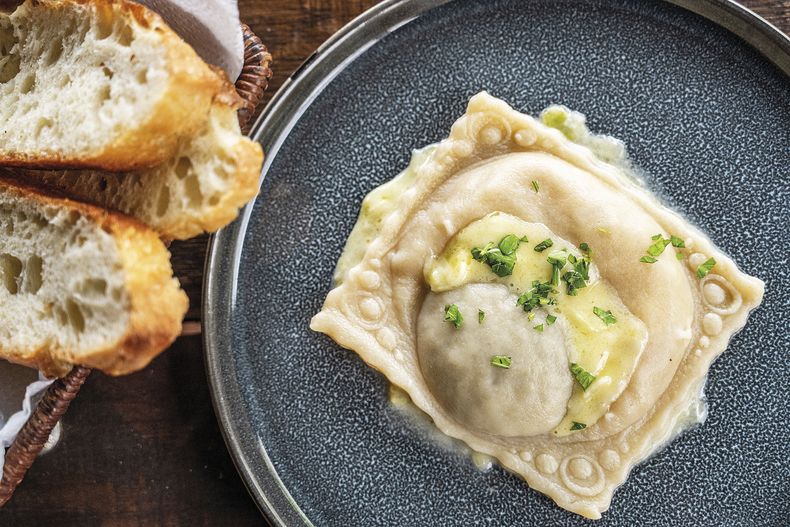 Raviolón con dos rellenos: uno de pato cocinado con brandy, champiñones, naranja y hierbas aromáticas, y otro de peras asadas. Acompañado de crema de puerros.