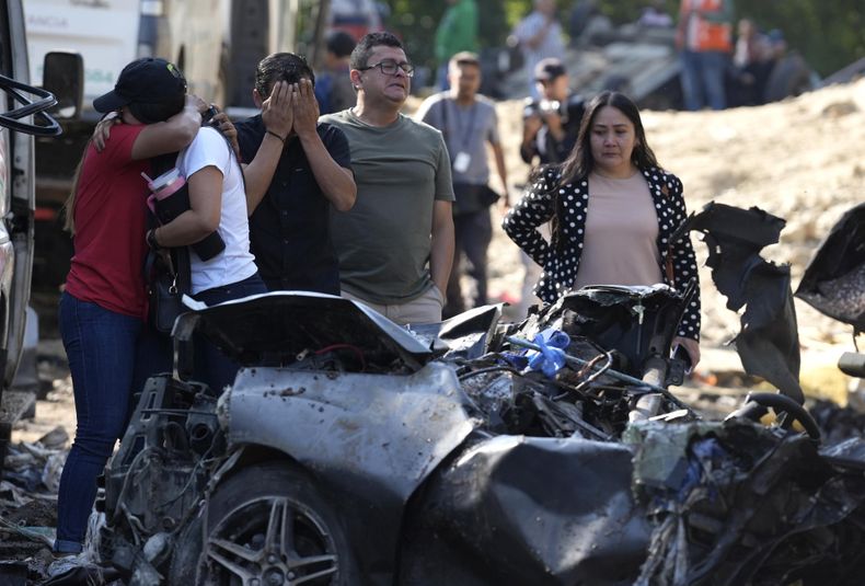 Familiares de las víctimas del atentado ocurrido en la Vía Panamericana lloran este domingo frente a los escombros de los vehículos destruidos, en Cajibío (Colombia).