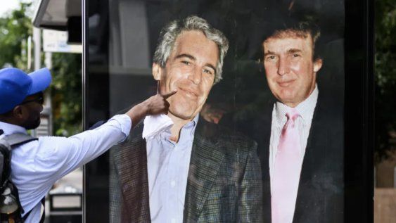 Un hombre señala una fotografía de Donald Trump y Jeffrey Epstein colocada extraoficialmente en una parada de ómnibus el 17 de julio en Londres de 2025.