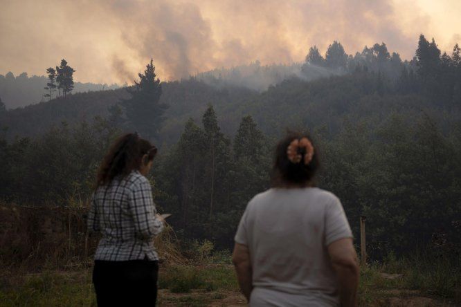 Dos mujeres observan un incendio forestal este lunes, en la comuna de Chaimávida, en Concepción a unos 491 km aproximadamente de Santiago (Chile).
