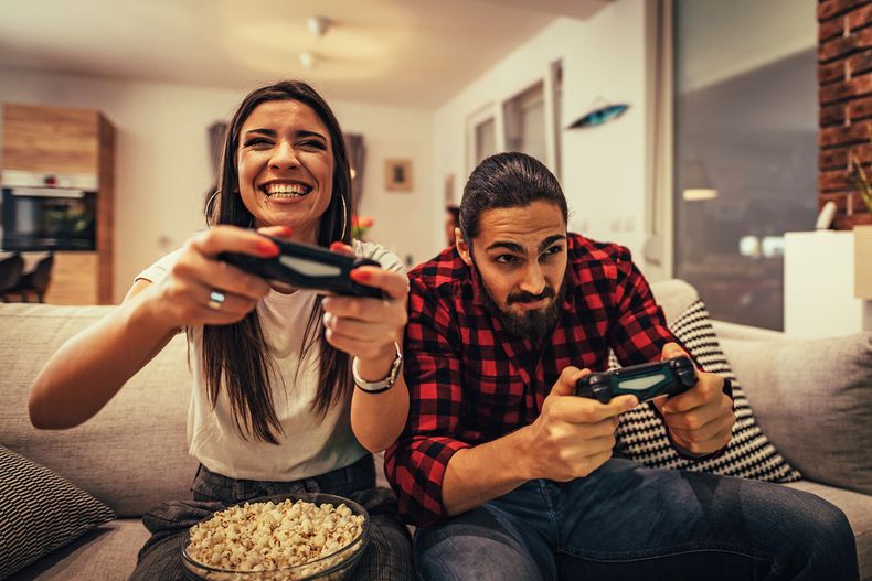 una-pareja-emocionada-esta-jugando-videojuegos-en-casa-sentada-en-un-sofa-tienen-un-gran-fin-de-semana-en-buena-compania-en-el-interior