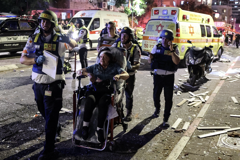 Una mujer herida es evacuada en silla de ruedas en una zona impactada por un misil lanzado desde Irán, en Ramat Gan, cerca de Tel Aviv, el 13 de junio de 2025