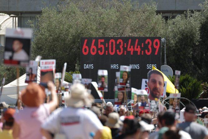 Un contador de tiempo digital muestra los días y horas transcurridos desde el 7 de octubre de 2023, mientras familiares y simpatizantes de los rehenes israelíes retenidos por Hamás en Gaza sostienen fotografías de los rehenes durante una manifestación exigiendo un alto el fuego y un acuerdo para la liberación de los rehenes, frente al cuartel general militar de Kirya en Tel Aviv, Israel, el 2 de agosto de 2025