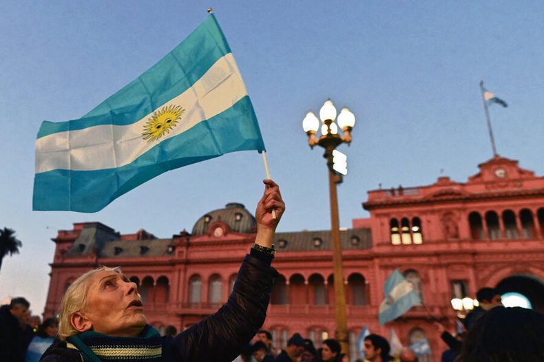 Una mujer sostiene la bandera argentina frente a la Casa Rosada, en Buenos Aires. Foto: AFP / Luis Robayo