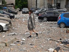 Residente camina entre autos dañados al salir de un edificio parcialmente destruido después de ataques con drones en Kiev. Foto: Oleksandr Popenko, PIJL