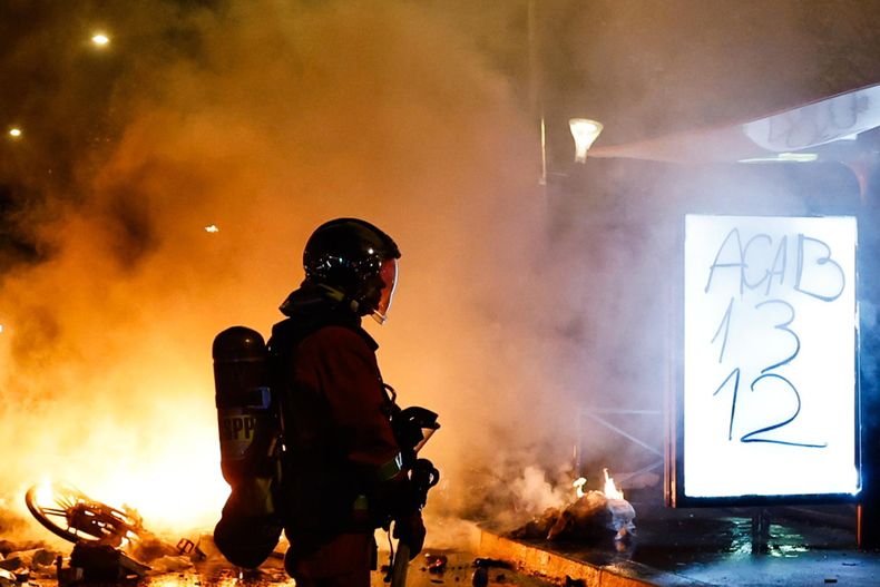 Un bombero francés acude a sofocar el incendio de una barricada en París, Francia, el 18 de octubre de 2026, en el marco de los enfrentamientos entre la policía antidisturbios y los manifestantes.