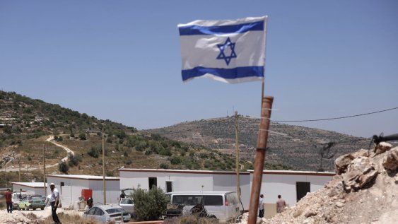 Una bandera israelí ondea cerca de estructuras prefabricadas, cerca del asentamiento de Maale Levona en la Cisjordania ocupada.
