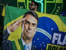 Un simpatizante del candidato a la Presidencia de Brasil por el Partido Liberal, Flávio Bolsonaro, sostiene una bandera con su rostro en un acto de campaña llamado bloquinho 22, cerca al Estadio Arena Castelão en Fortaleza, Ceará (Brasil).