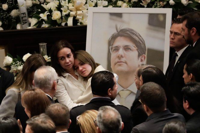 La esposa del fallecido senador y precandidato a la presidencia de Colombia Miguel Uribe Turbay, Claudia Tarazona (c-i), abraza a una de sus hijas frente a una fotografía de Miguel, en el Salón Elíptico del Capitolio Nacional en Bogotá (Colombia)