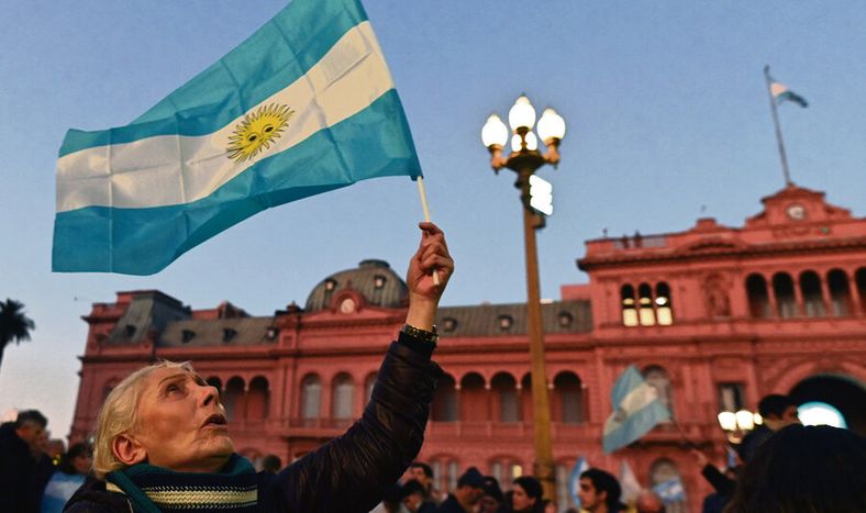 Una mujer sostiene la bandera argentina frente a la Casa Rosada, en Buenos Aires. Foto: AFP / Luis Robayo