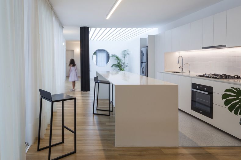 La isla de cuarzo blanco aldán, las butacas Flaca de Mass arquitectos y el piso de porcelanato conforman el área de la cocina. Fotos: Marcos Guiponi