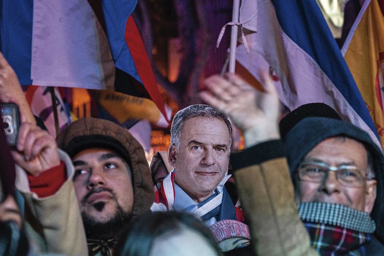 Una máscara con la cara del candidato Yamandú Orsi destaca entre la multitud.