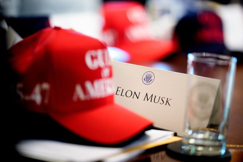 Gorro de Donald Trump junto a un cartel con el nombre de Elon Musk durante una reunión en la Casa Blanca, el 30 de abril de 2025