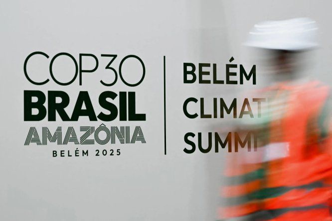 Un trabajador pasa junto a una pancarta con el logotipo de la Conferencia sobre el Cambio Climático COP30.