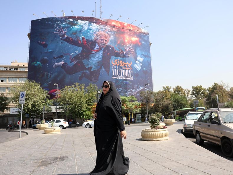 Una mujer iraní con velo pasa junto a una valla publicitaria antiestadounidense con la imagen del presidente estadounidense Donald Trump en el sur de Teherán, Irán, el 24 de agosto de 2026.